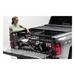 Woman loading tool in Roll-N-Lock Cargo Manager for 20-22 Jeep Gladiator, truck bed.