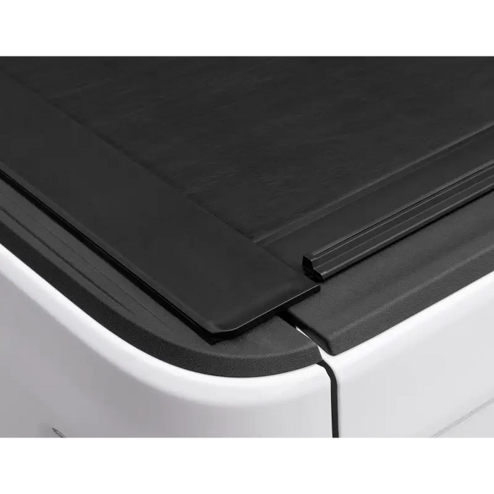 Side view of Roll-N-Lock retractable tonneau cover on black truck bed door.