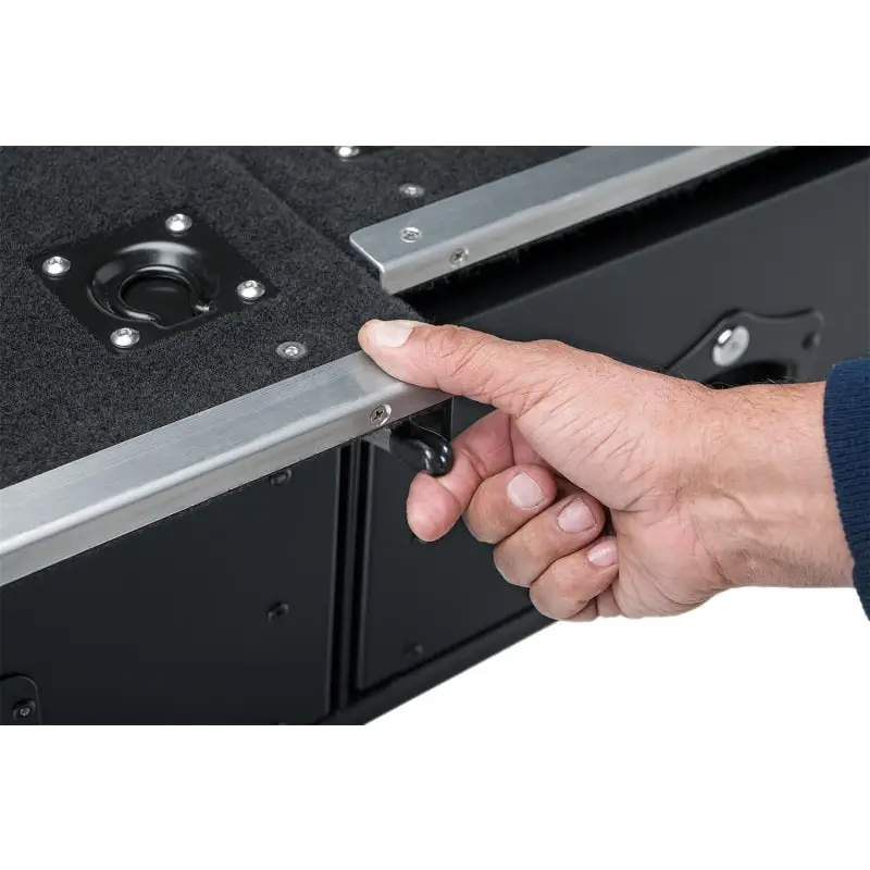 Hand holding metal latch on black cabinet of Rugged Ridge cargo storage drawers.