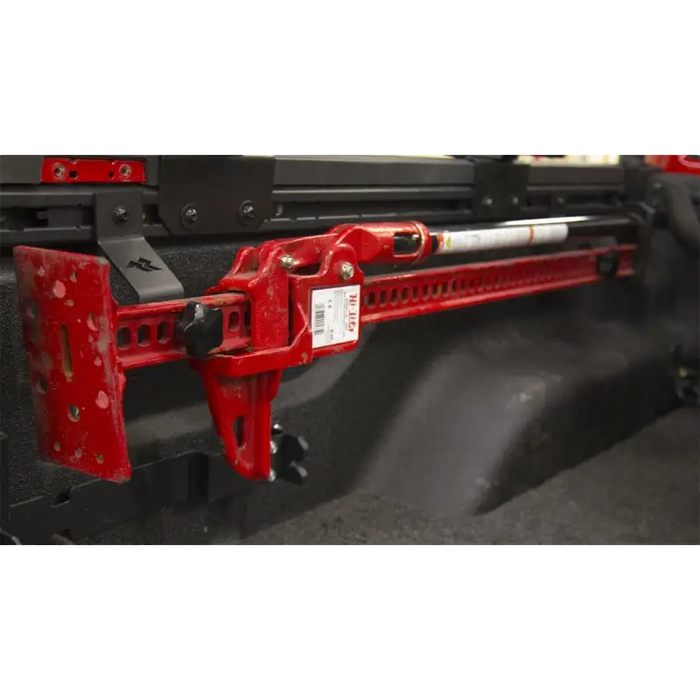 Red truck with black and white bumpers on a Rugged Ridge off-road jack bed rail mount.