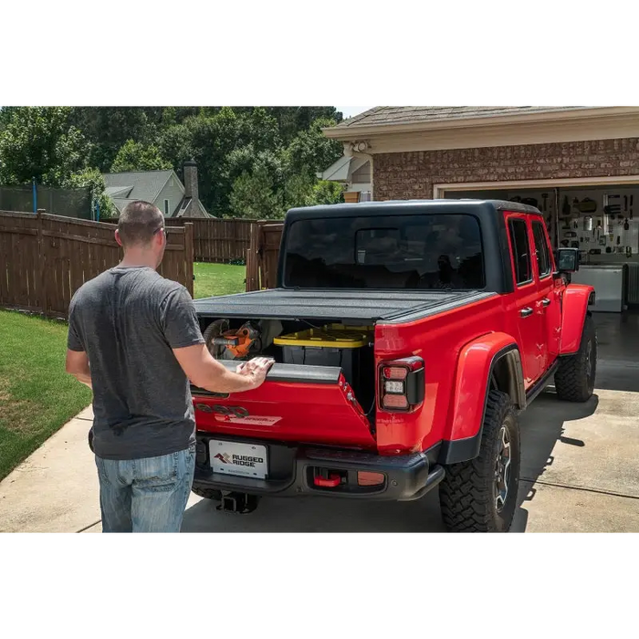 Man loading truck bed with Armis Hard Folding cover by Rugged Ridge