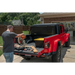 Man putting wood in red Jeep trunk with Rugged Ridge Armis Hard Folding Bed Cover.