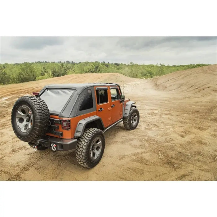 Rugged Ridge Bowless Soft Top Black Diamond on Jeep Wrangler JK driving on dirt road.