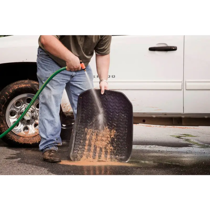 Man using hose to clean tire on Rugged Ridge floor liner for Jeep Wrangler.