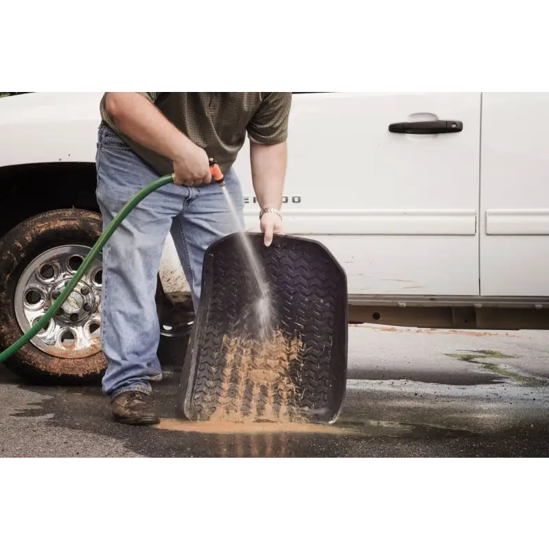 Man cleaning tire with Rugged Ridge floor liner for Jeep Wrangler.