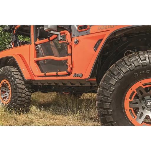 Jeep Wrangler JL 2-Door with rugged ridge rocker guard and orange wheels parked in a field.