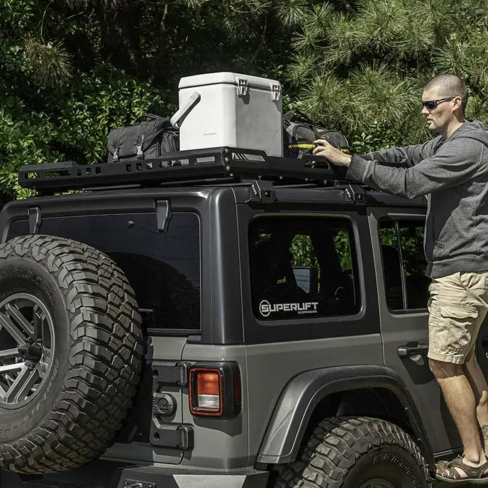 Man installing tire on Jeep with Rugged Ridge Roof Rack for 18-20 Jeep Wrangler JL 4Dr Hardtops