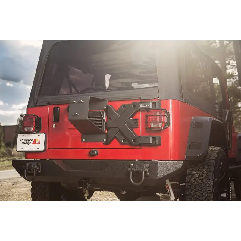 Red Jeep with black top parked on road, showcasing Rugged Ridge Spartacus HD Tire Carrier Kit.