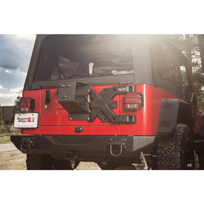 Red Jeep with black top parked on road, showcasing Rugged Ridge Spartacus HD Tire Carrier Wheel Mount 87-06 YJ/TJ.