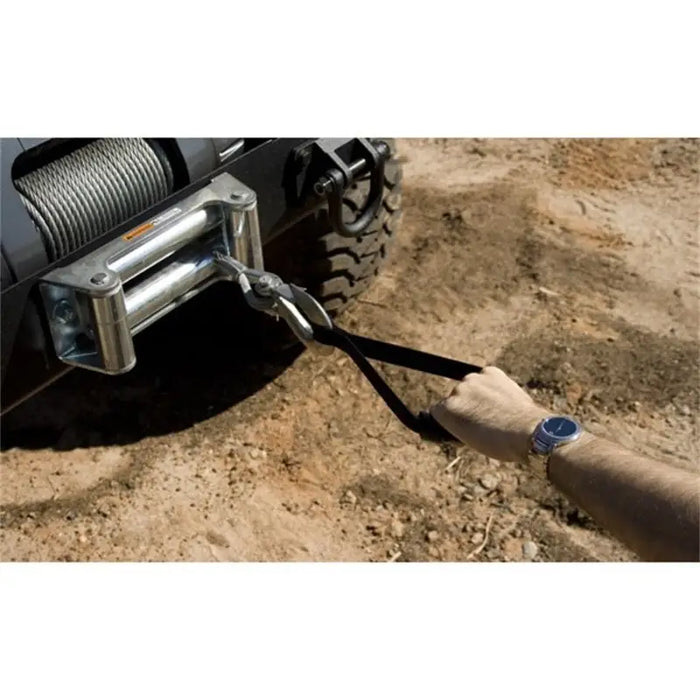 Rugged Ridge winch safety strap with person pulling nylon webbing from the side of a jeep wrangler