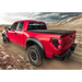 Red truck driving down dirt road with Truxedo 05-15 Toyota Tacoma 5ft Lo Pro Bed Cover.