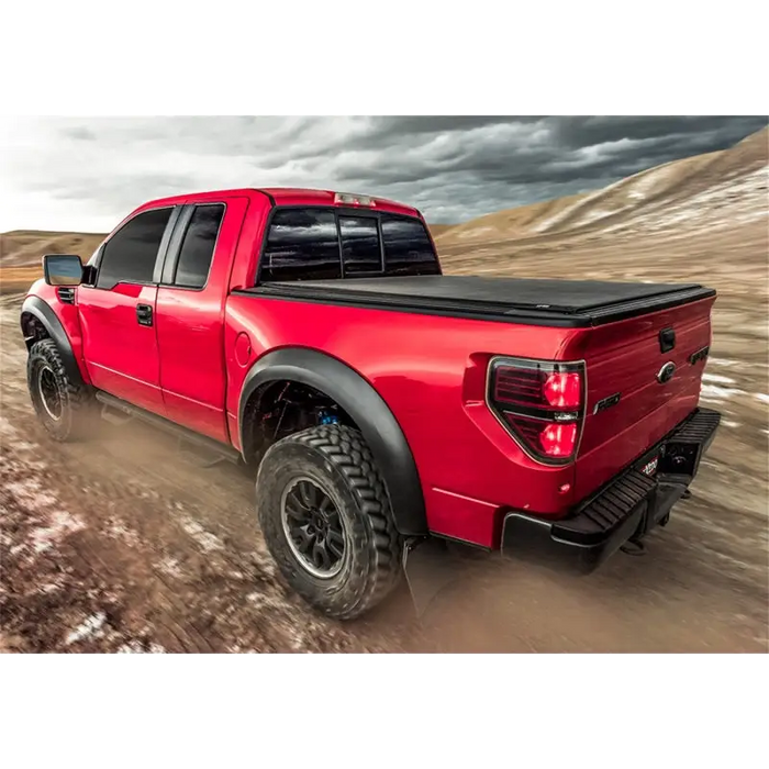 Red truck driving down dirt road with Truxedo 16-20 Toyota Tacoma 5ft Lo Pro Bed Cover