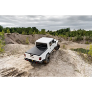 Truck driving on dirt road with Truxedo 2020 Jeep Gladiator 5ft Lo Pro bed cover.