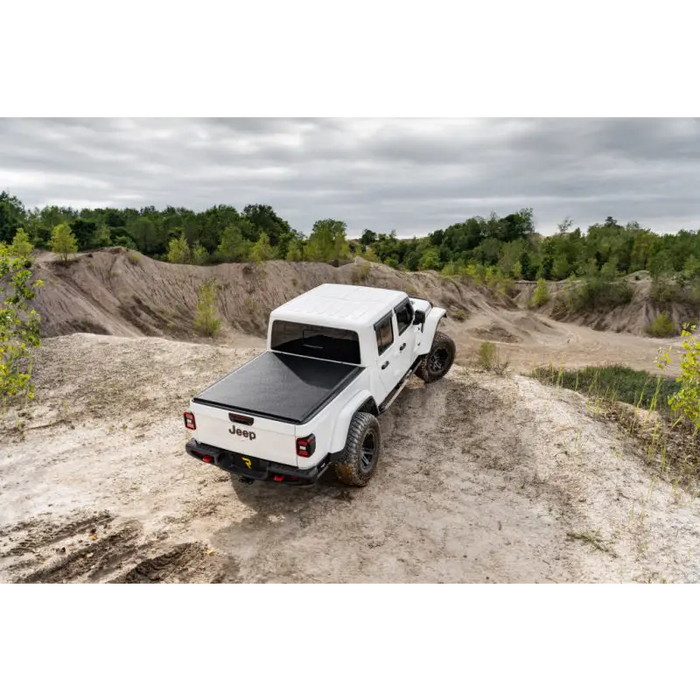 Truck driving on dirt road with Truxedo 2020 Jeep Gladiator 5ft Lo Pro bed cover.