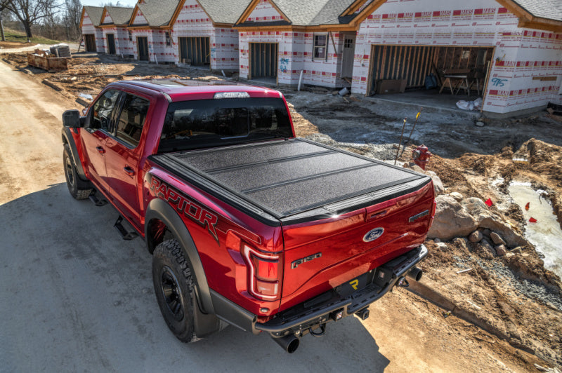 Red truck parked at construction site in front of undercover 16-20 toyota tacoma 5ft armor flex bed cover - black textured