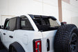 White truck with black bed and tire featuring dv8 ford bronco rear window molle panels.