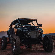 Rigid industries revolve light pod with amber trim ring shining on black utv at sunset