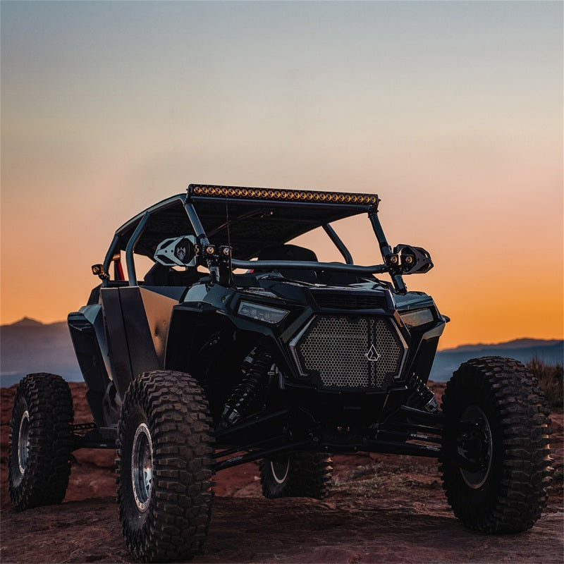 Rigid industries revolve light pod with amber trim ring shining on black utv at sunset