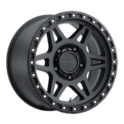 A black wheel with a center hole and rivets on the rim